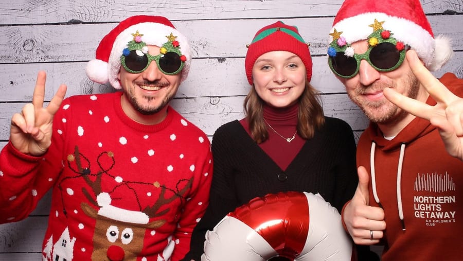 Lachende Gäste in Weihnachts-Outfits mit perfekt belichteten Fotobox-Fotos