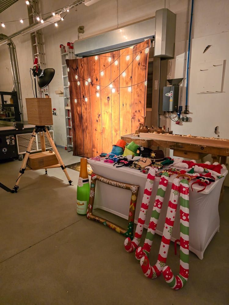 Fotobox-Aufbau mit Holzwand, Lichterketten und Requisitentisch auf einer Weihnachtsfeier